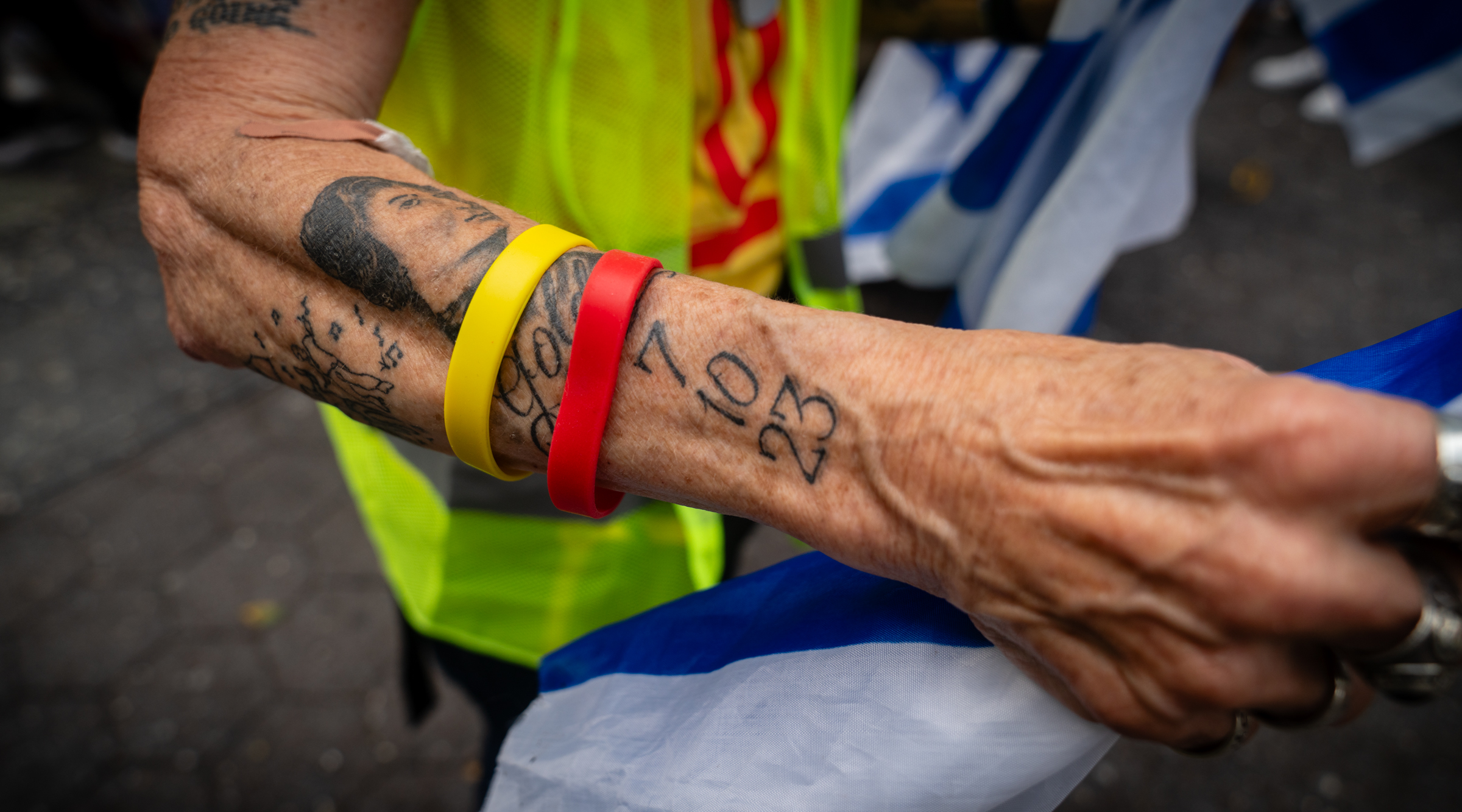 A volunteer with the Hostages and Missing Families Forum shows a tattoo commemorating the Oct. 7 attack at a rally for the hostages in midtown Manhattan. Volunteers handed out stickers with the number 